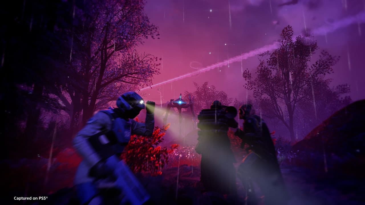 A Helldivers squad fires across a purple-lit battlefield in official PS5 capture.