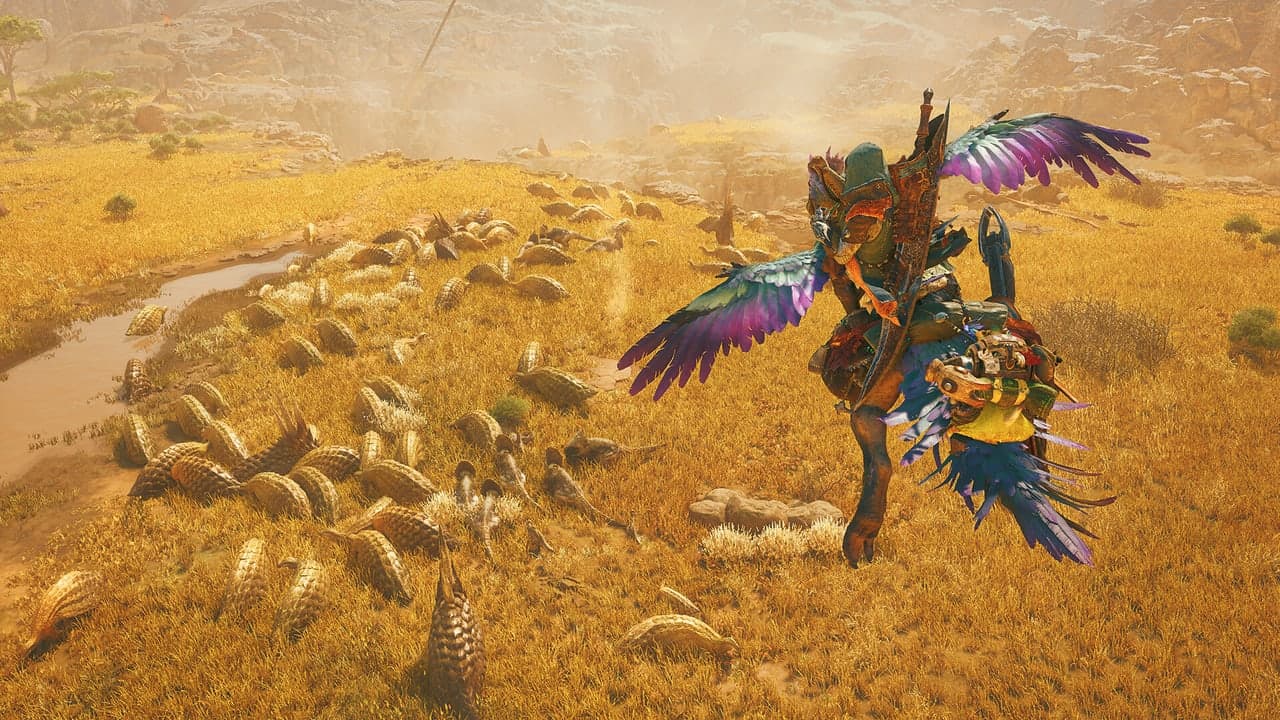 A hunter and a brightly feathered mount cross a grassy Monster Hunter Wilds landscape.